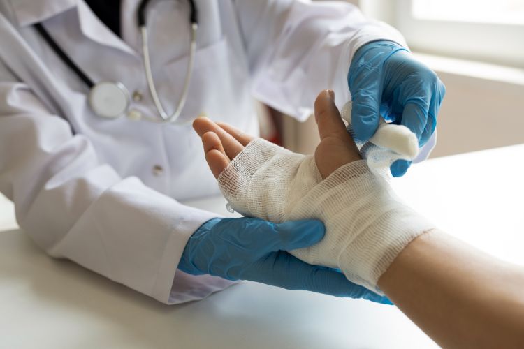 un medico avvolge con una garza la mano del paziente dopo un’ustione